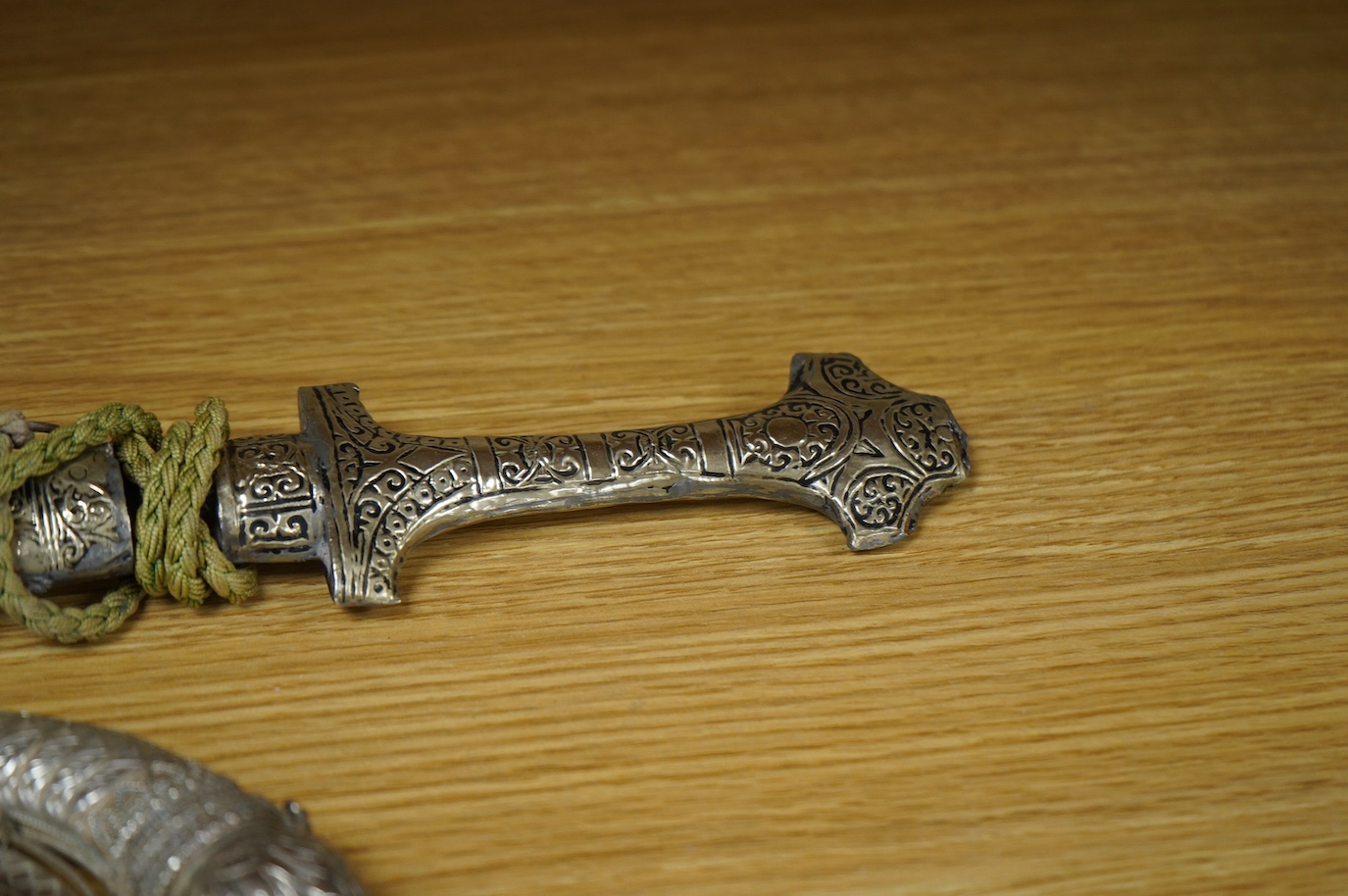 An Omani silver spice box in the form of a curved powder flask, together with a Moroccan dagger Jambiya with nickel hilt and sheath, both 20th century. Condition - fair.